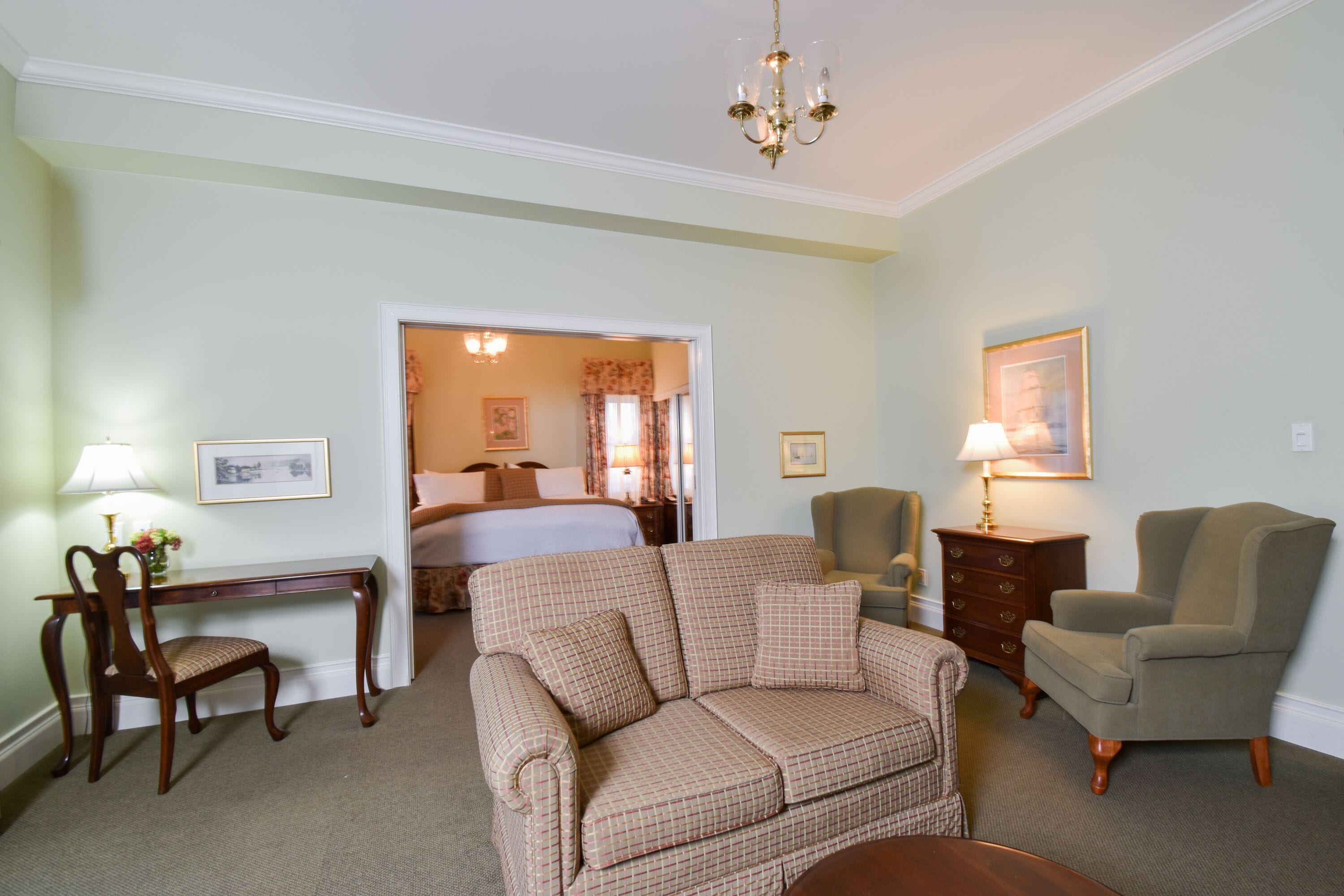 Ein Hotelzimmer mit Bett, Sofa, Schreibtisch, Stuhl und Lampe.