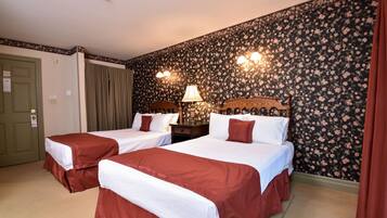 Habitación de hotel con dos camas individuales, una mesita de noche con lámpara, papel tapiz floral y una puerta con un letrero.