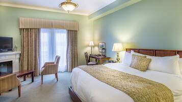 Une chambre d’hôtel avec un grand lit, un bureau, une chaise, une télévision et une cheminée.