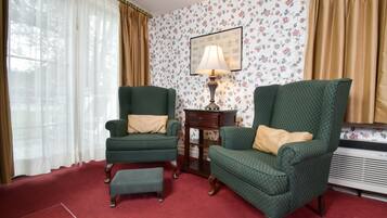 A room with two green armchairs, a small table, a lamp, and a radiator.