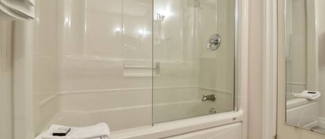 Une salle de bain moderne avec une douche à parois de verre, une baignoire blanche et un miroir qui reflète la pièce.