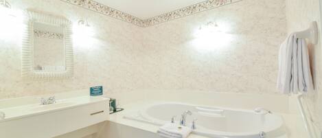 Une salle de bain avec une grande baignoire, un double vasque et un miroir.