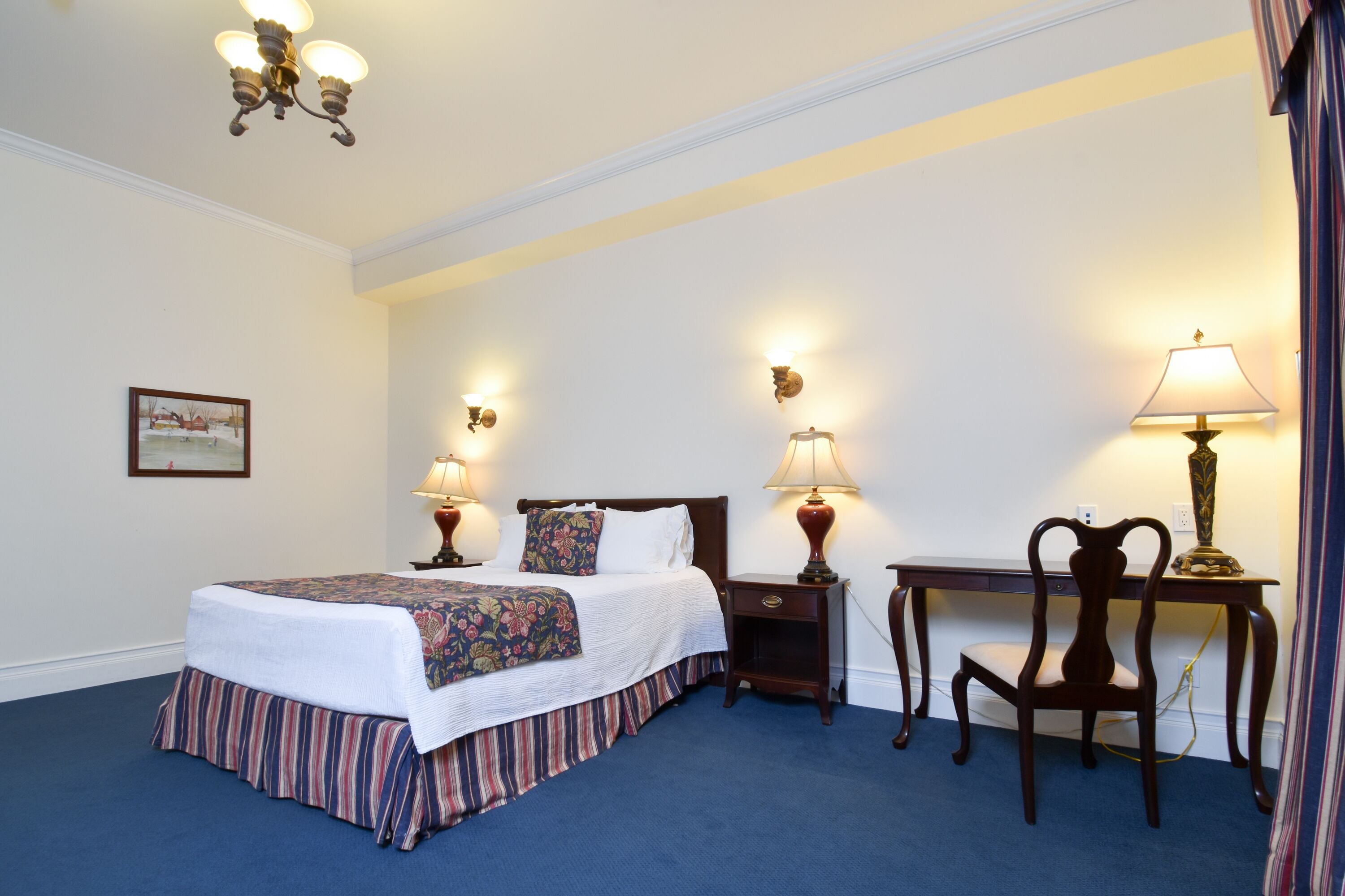 A neatly arranged hotel room with a bed, bedside tables with lamps, a desk, and a chair.