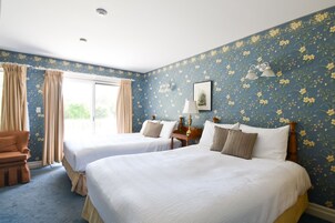 Une chambre d’hôtel avec deux lits, un canapé, une lampe et une fenêtre avec des rideaux.
