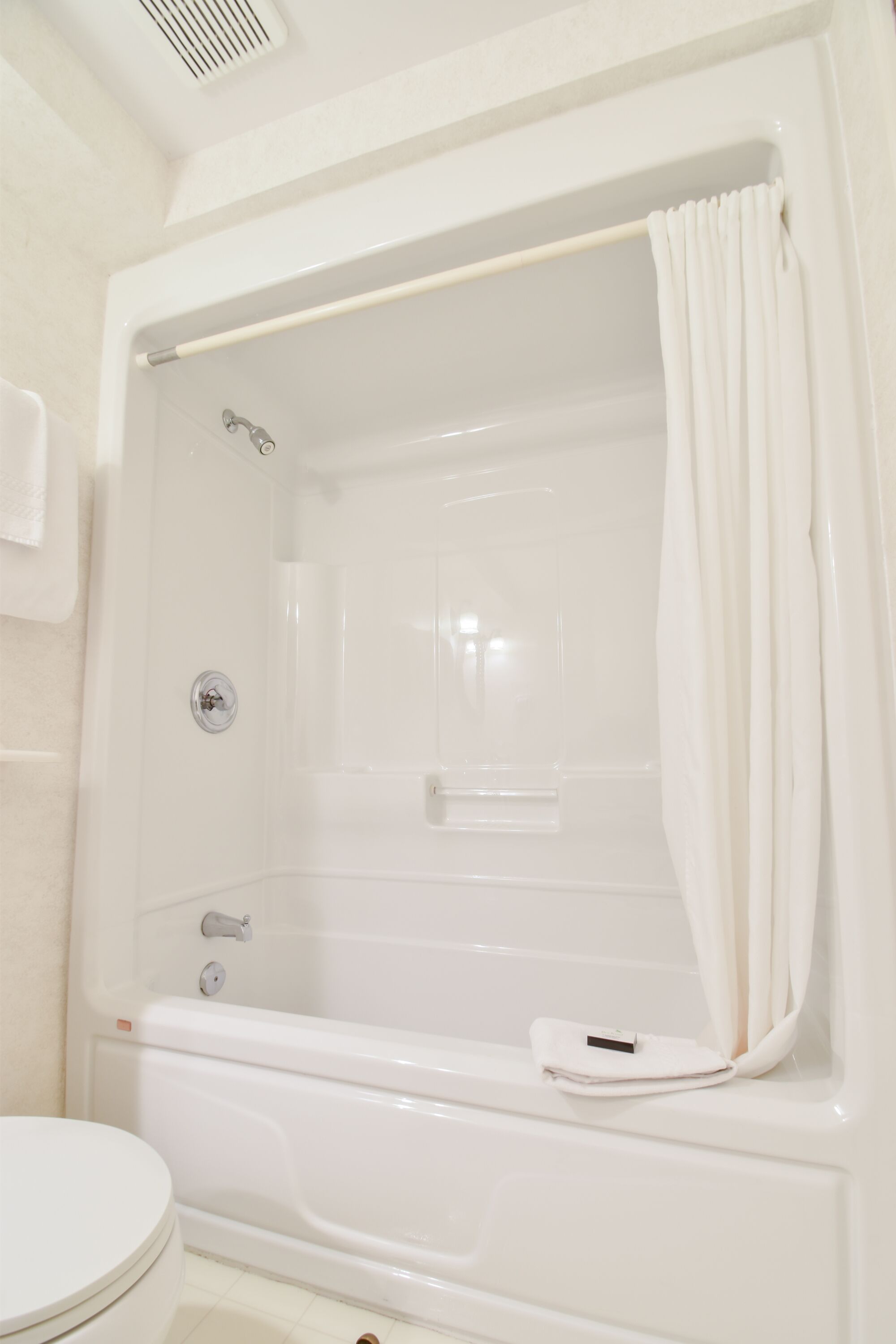 Una bañera blanca con ducha, perchero y retrete.