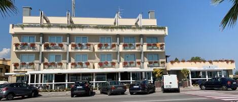 Un hotel con varios balcones, un estacionamiento y cielo despejado.