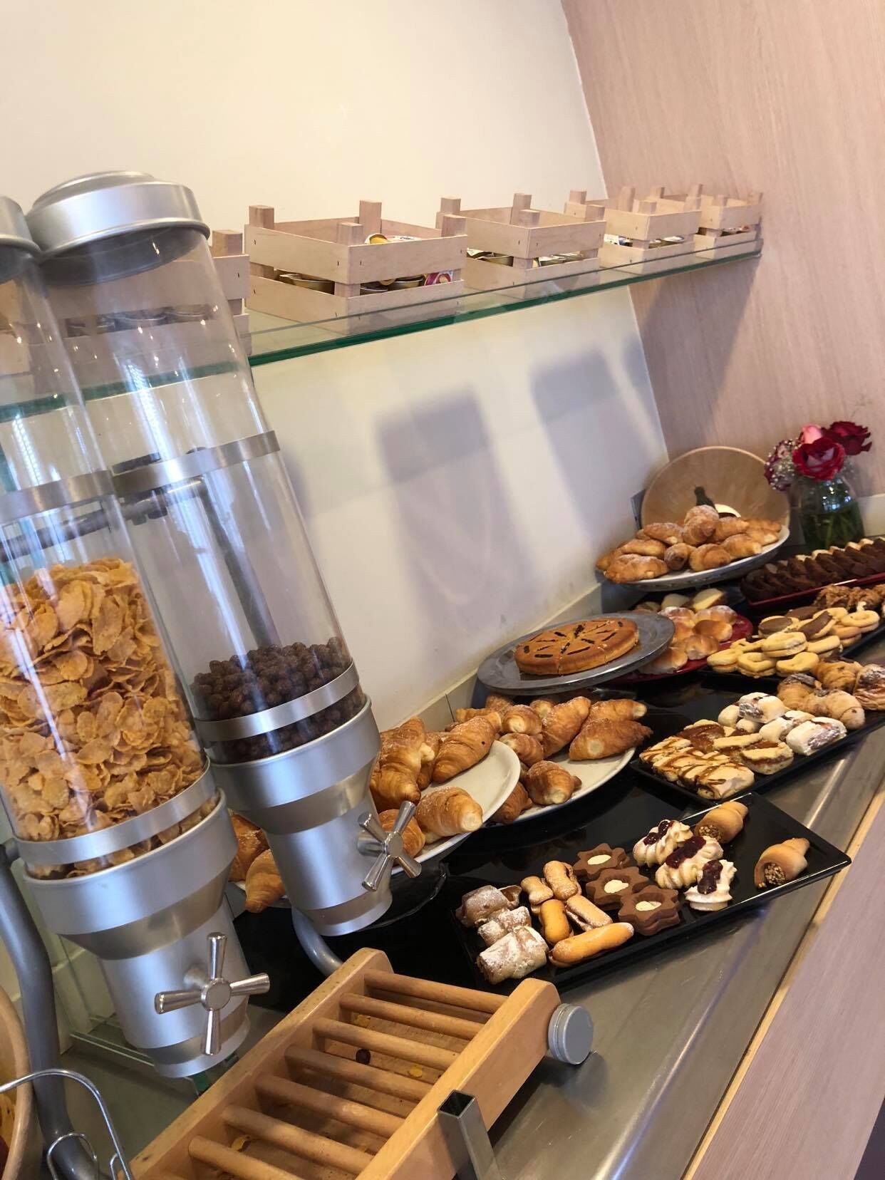 A buffet with various food items including cereals, pastries, and desserts.