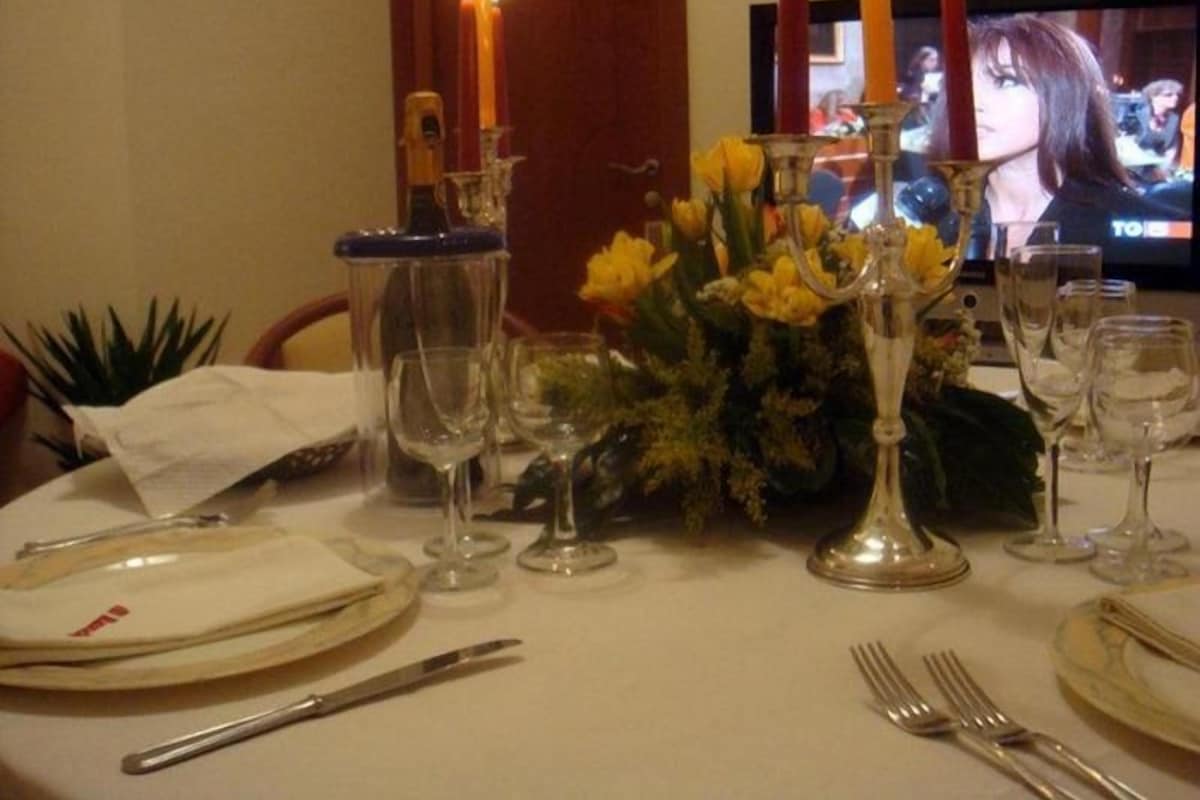 A dining table set with plates, cutlery, glasses, and candles.