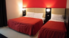 A hotel room with two beds, each with a red bedspread, white pillows, and a beige headboard. There are two wall-mounted nightstands with lamps. - Rama Palace Hotel (Casalnuovo di Napoli)