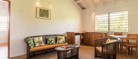 A spacious living area with a wooden bench, a round coffee table, and a dining table with chairs.