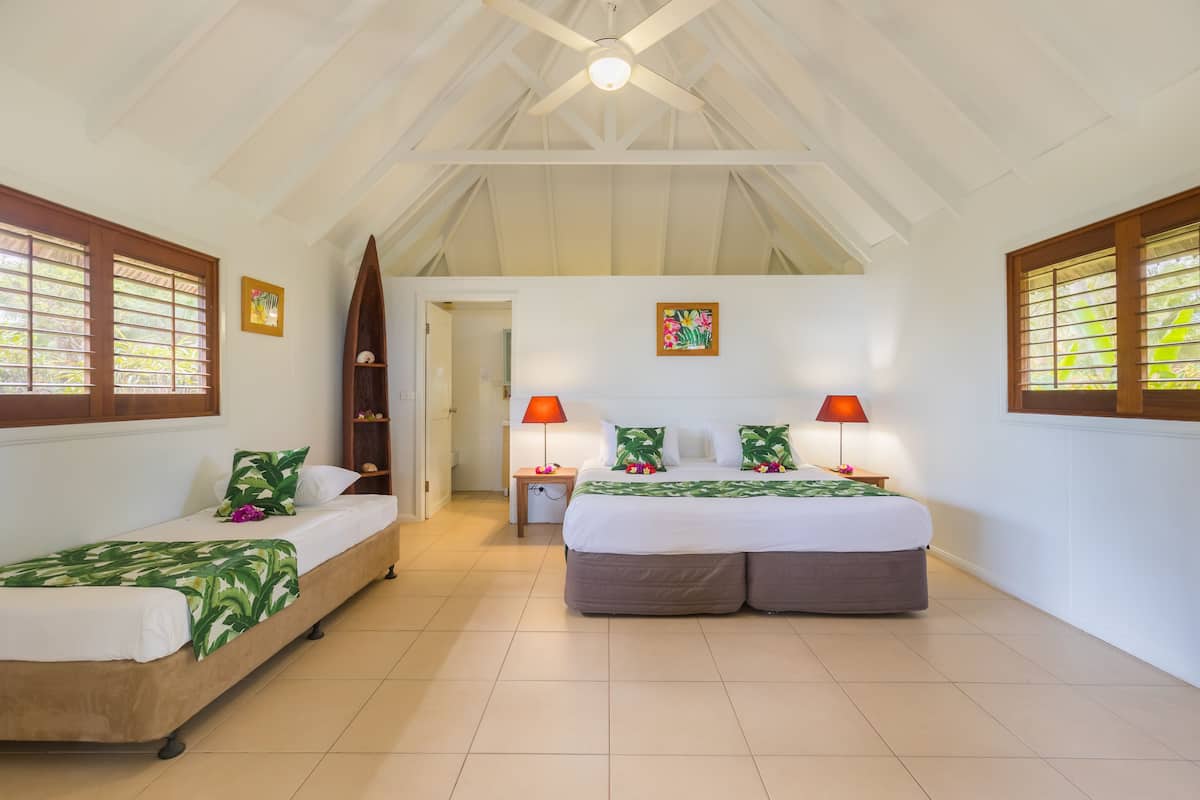 Een slaapkamer met twee bedden, een houten plafond en een deur naar een andere kamer.