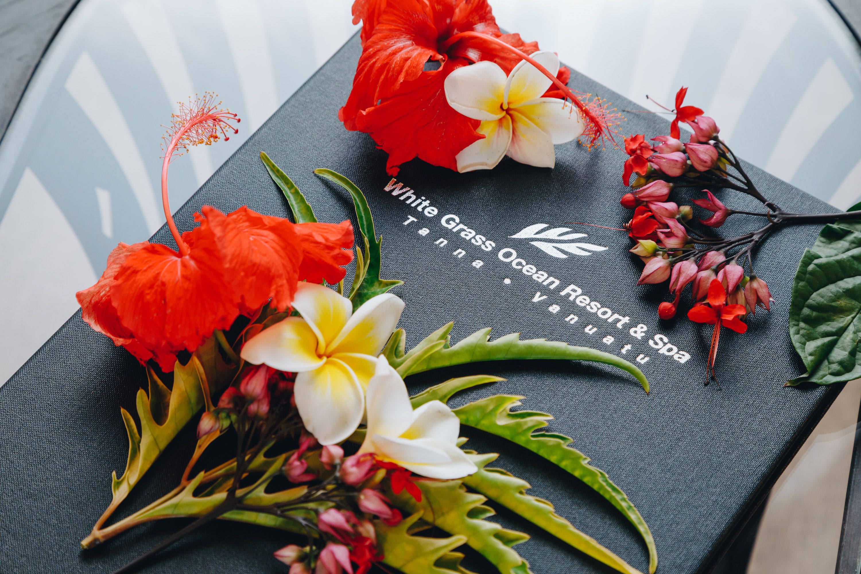 A black brochure with the text "White Grass Ocean Resort & Spa" and various tropical flowers.