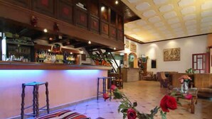 A bar area with stools, a counter, and a vase with roses. - Aiolos Hotel (Delphi)