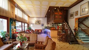 A spacious lobby with a high ceiling, a staircase, and a seating area with sofas and chairs. - Aiolos Hotel (Delphi)