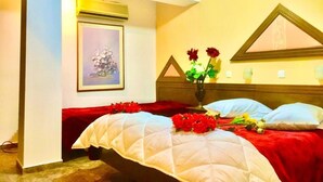 A hotel room with a bed, a painting on the wall, a vase with flowers, and a red blanket on the bed. - Aiolos Hotel (Delphi)