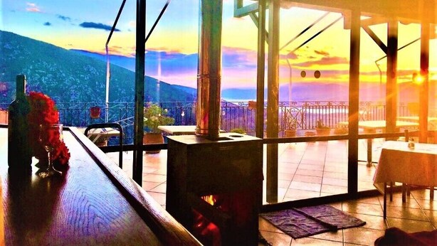 A restaurant with a large window overlooking a mountainous landscape. - Aiolos Hotel (Delphi)