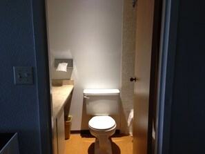 A small, narrow bathroom with a toilet, a sink, and a towel hanging on the wall.
