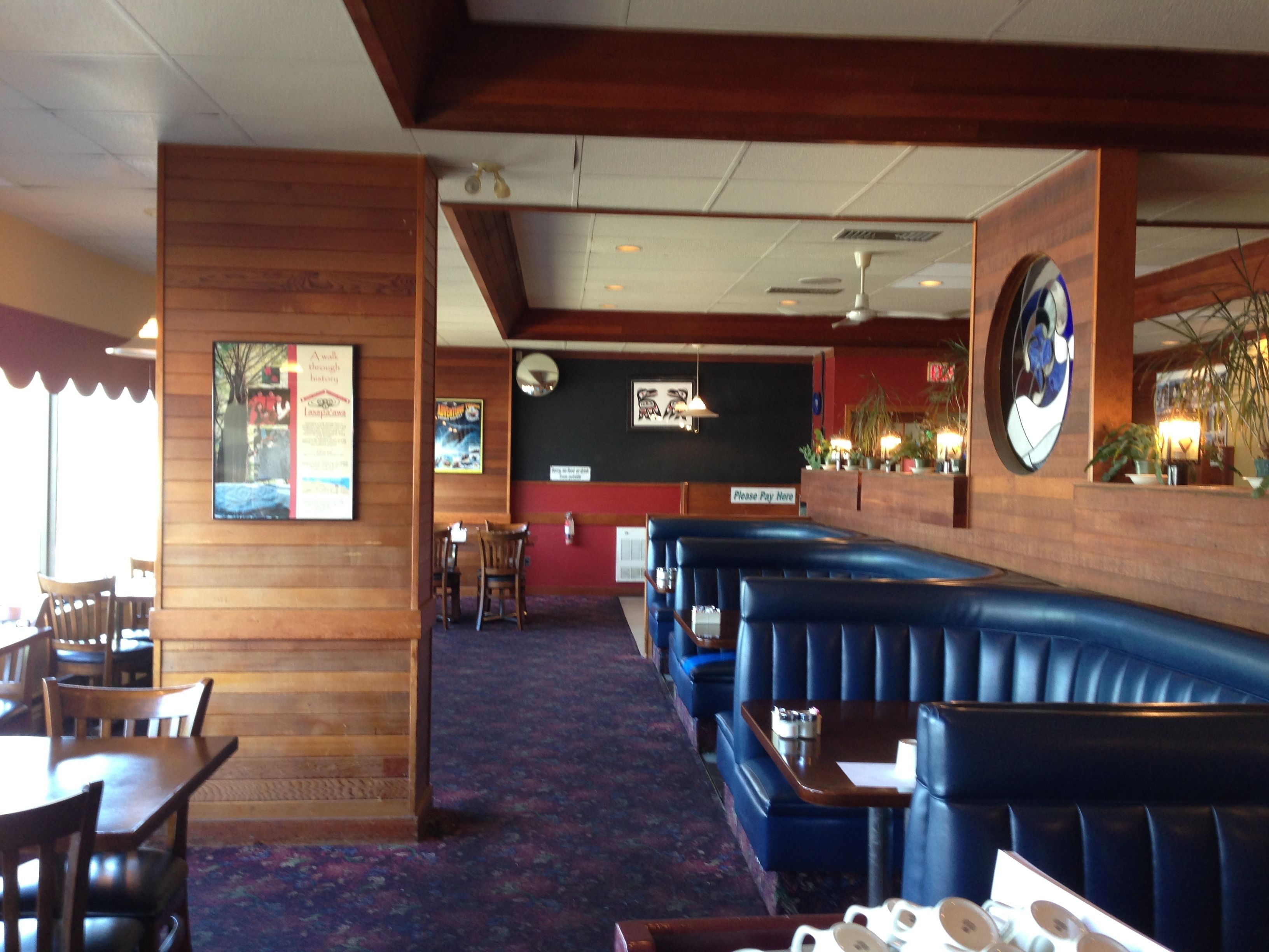 Een restaurant met houten wanden, blauwe zittingen en een vloerkleed.