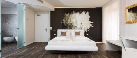 A modern bedroom with a large bed, a decorative wall piece, and a bathroom visible through an open door.