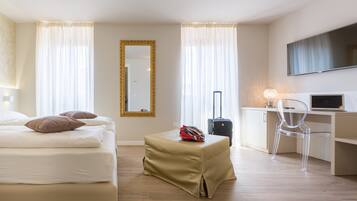 Una habitación de hotel con cama, escritorio, silla, maleta y televisión.