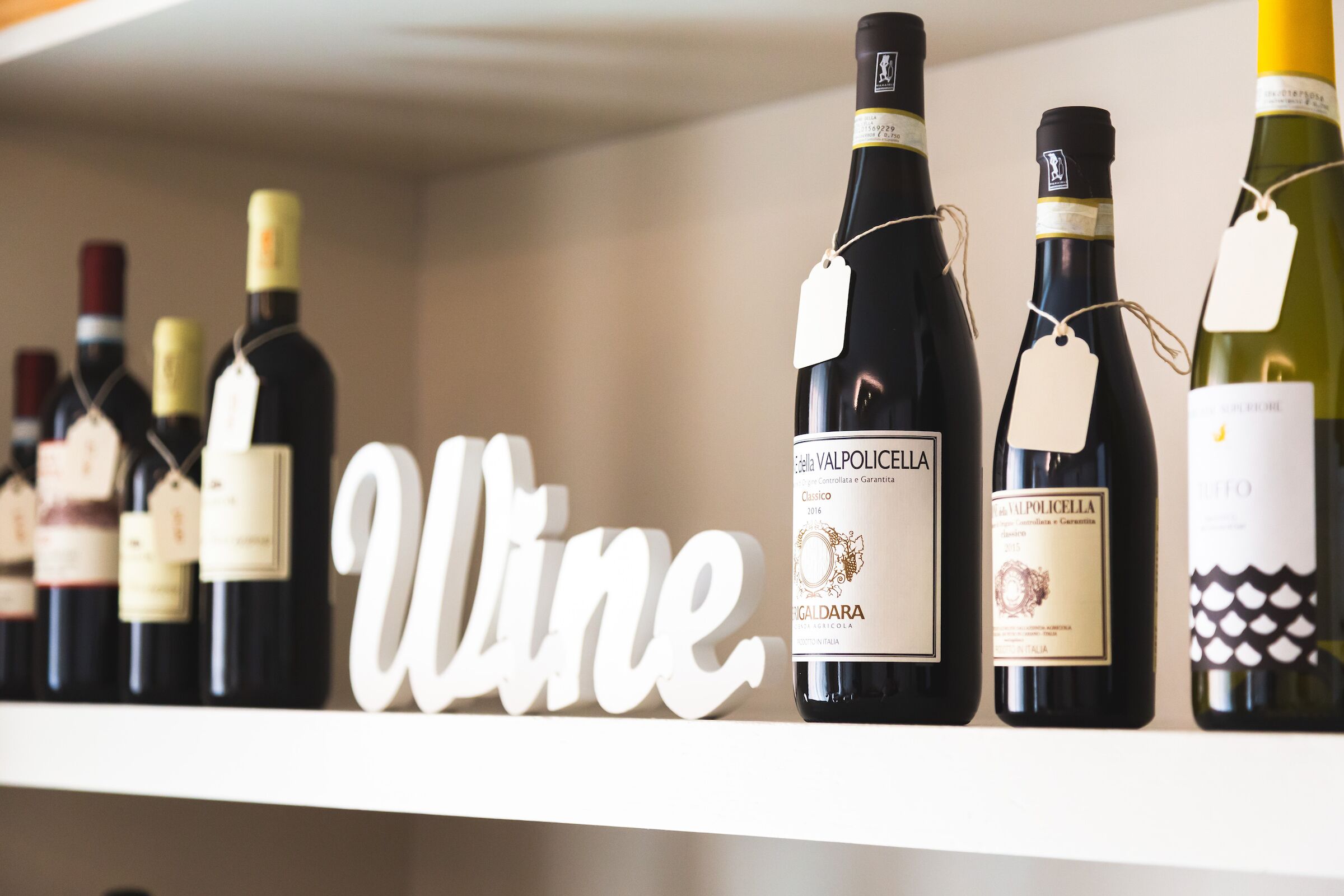 Una estantería con botellas de vino y un cartel que dice 'Wine'.