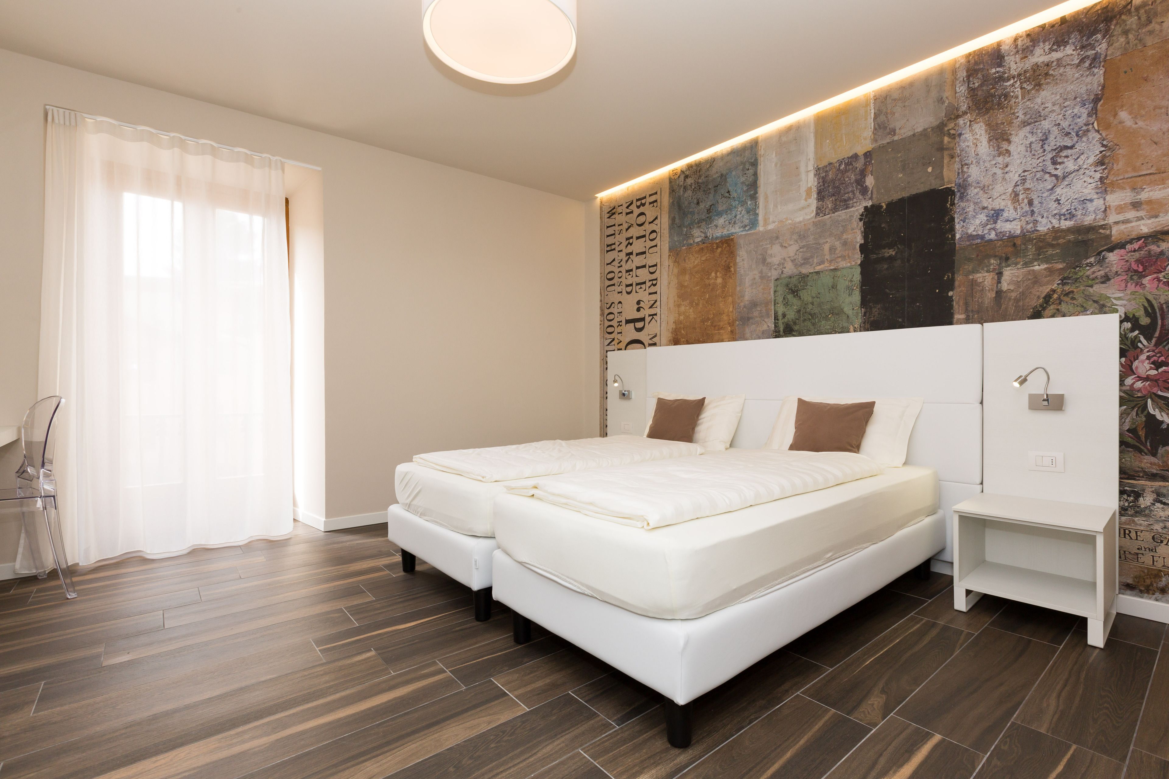 A modern bedroom with a large bed, a nightstand, and a wall with a textured mural.