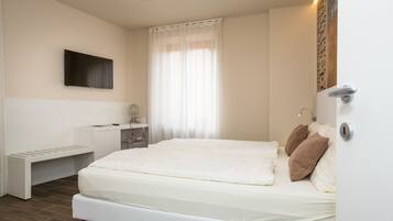 Un dormitorio moderno con una cama grande, una mesita de noche, un espejo y un televisor de pantalla plana montado en la pared.