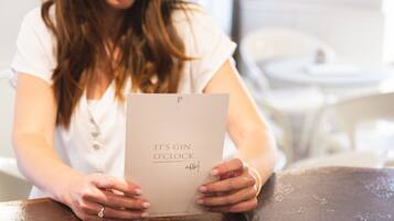 A person holding a book titled "It's Gin O'Clock" with a visible website URL.