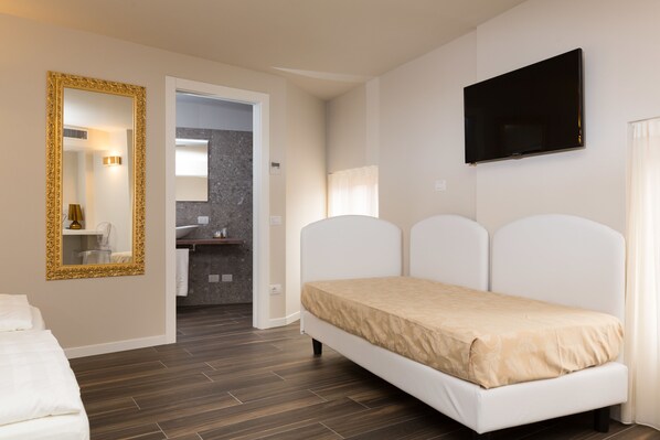 A bedroom with a bed, a TV, and a bathroom visible in the background.