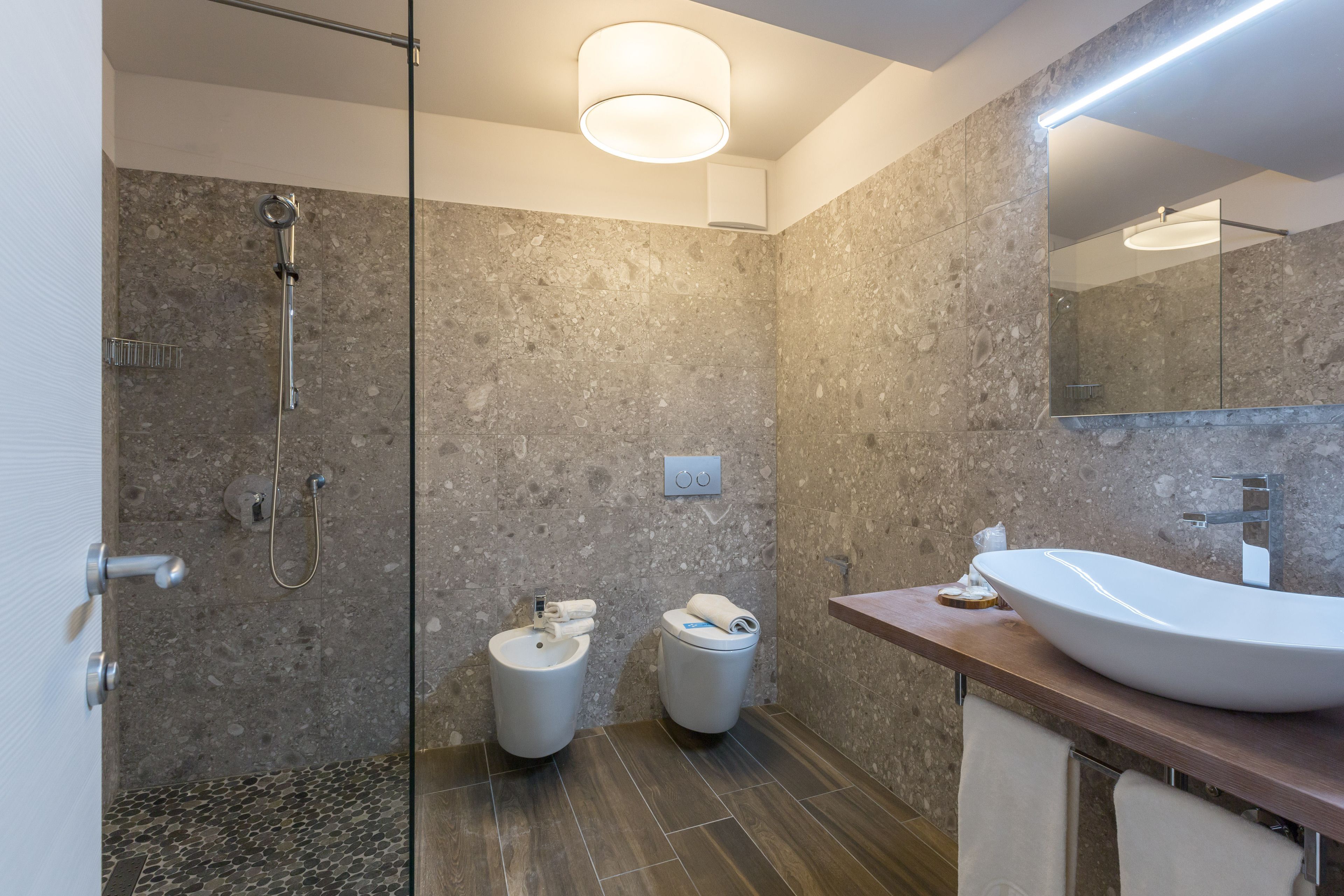 Een moderne badkamer met een douchecabine van glas, een grote spiegel en een wastafel.