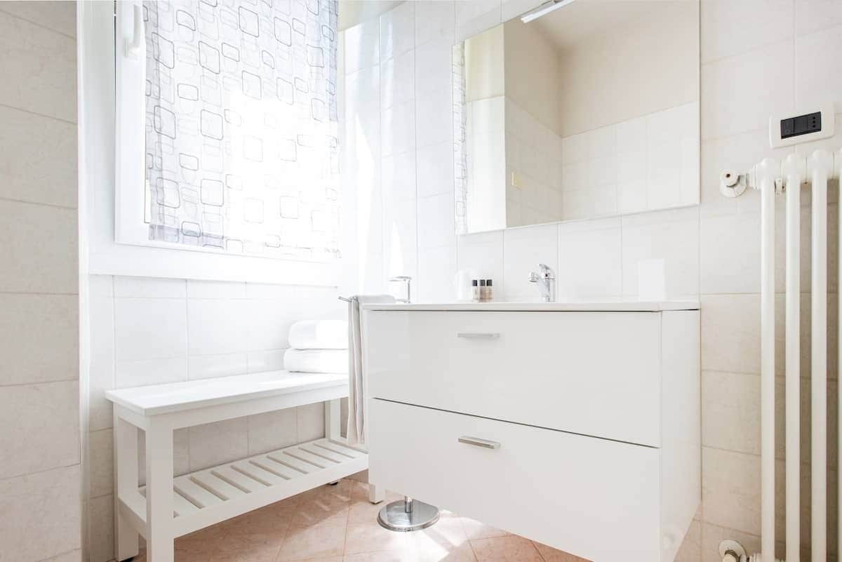 A bathroom with a white vanity, a mirror, and a radiator.