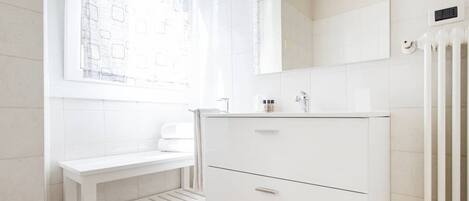 A bathroom with a white vanity, a mirror, and a radiator.