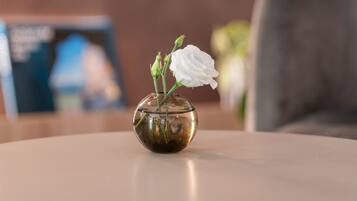 Uma mesa redonda com um vaso de vidro transparente contendo flores brancas.