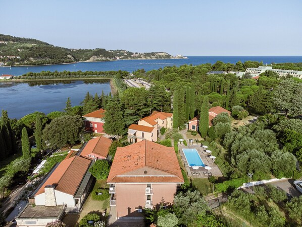 Un resort costero con varias construcciones, una piscina y vistas al mar.