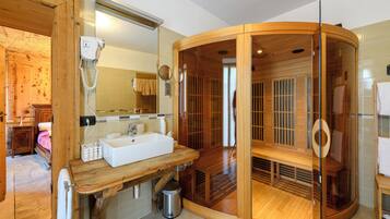 A wooden sauna with a glass door, a wooden bench, and a white sink with a mirror above it.