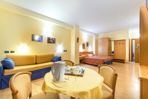 Una habitación acogedora con sofá, cama, mesa de comedor con sillas y una zona de kitchenette.