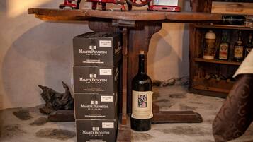 A wooden table with a wine press, a bottle of wine, and several boxes labeled "Mamete Prevostini."
