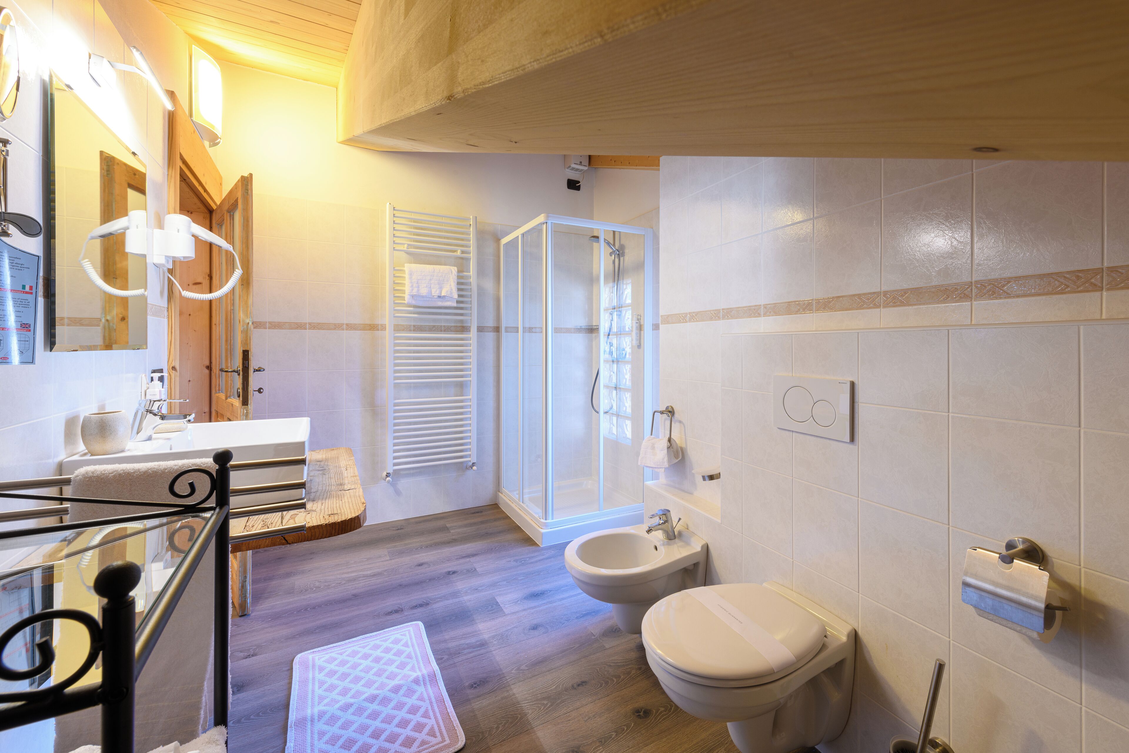 Un baño con piso de madera, cabina de ducha de vidrio, inodoro blanco y bidé.