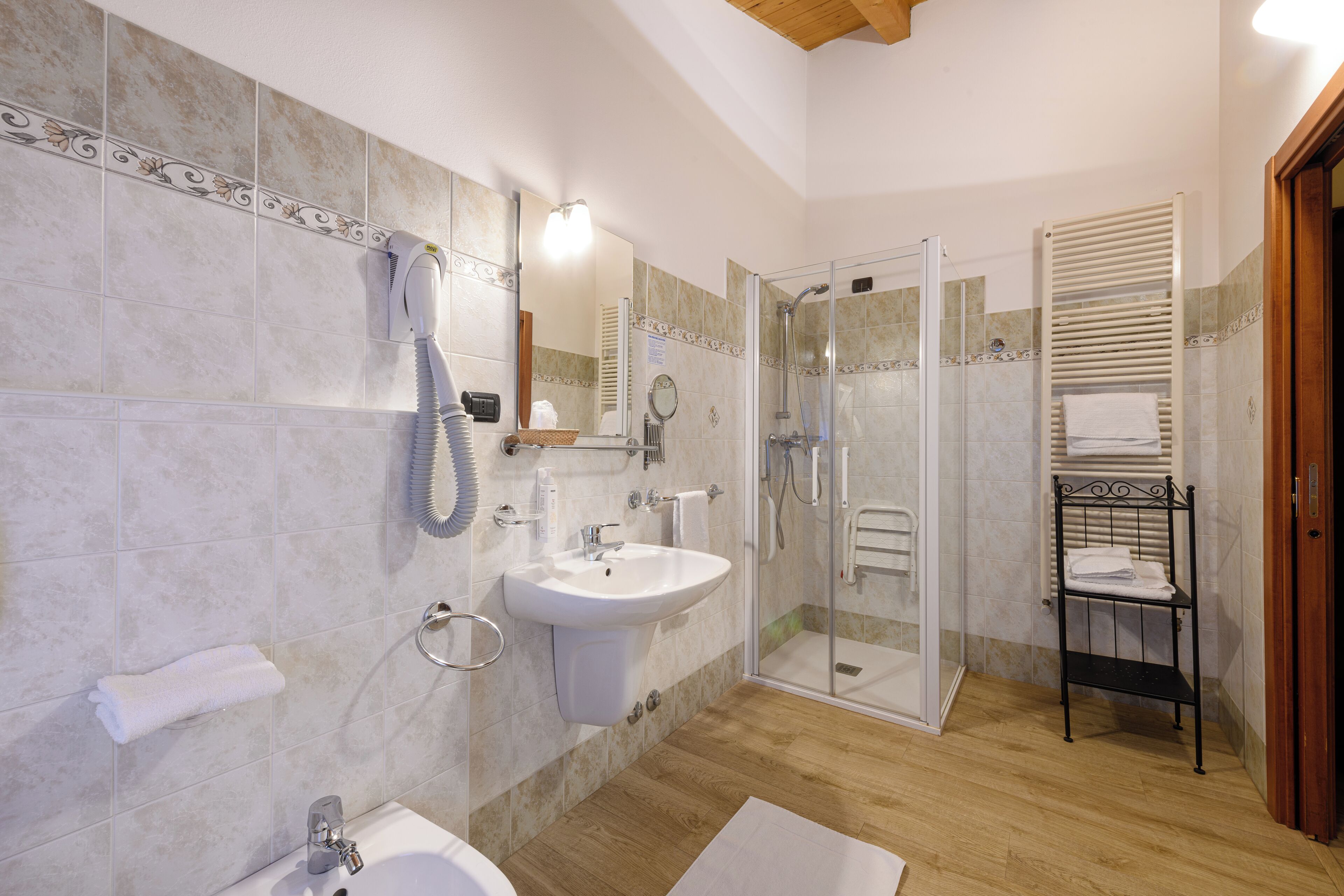 A bathroom with a shower, sink, and towel rack.