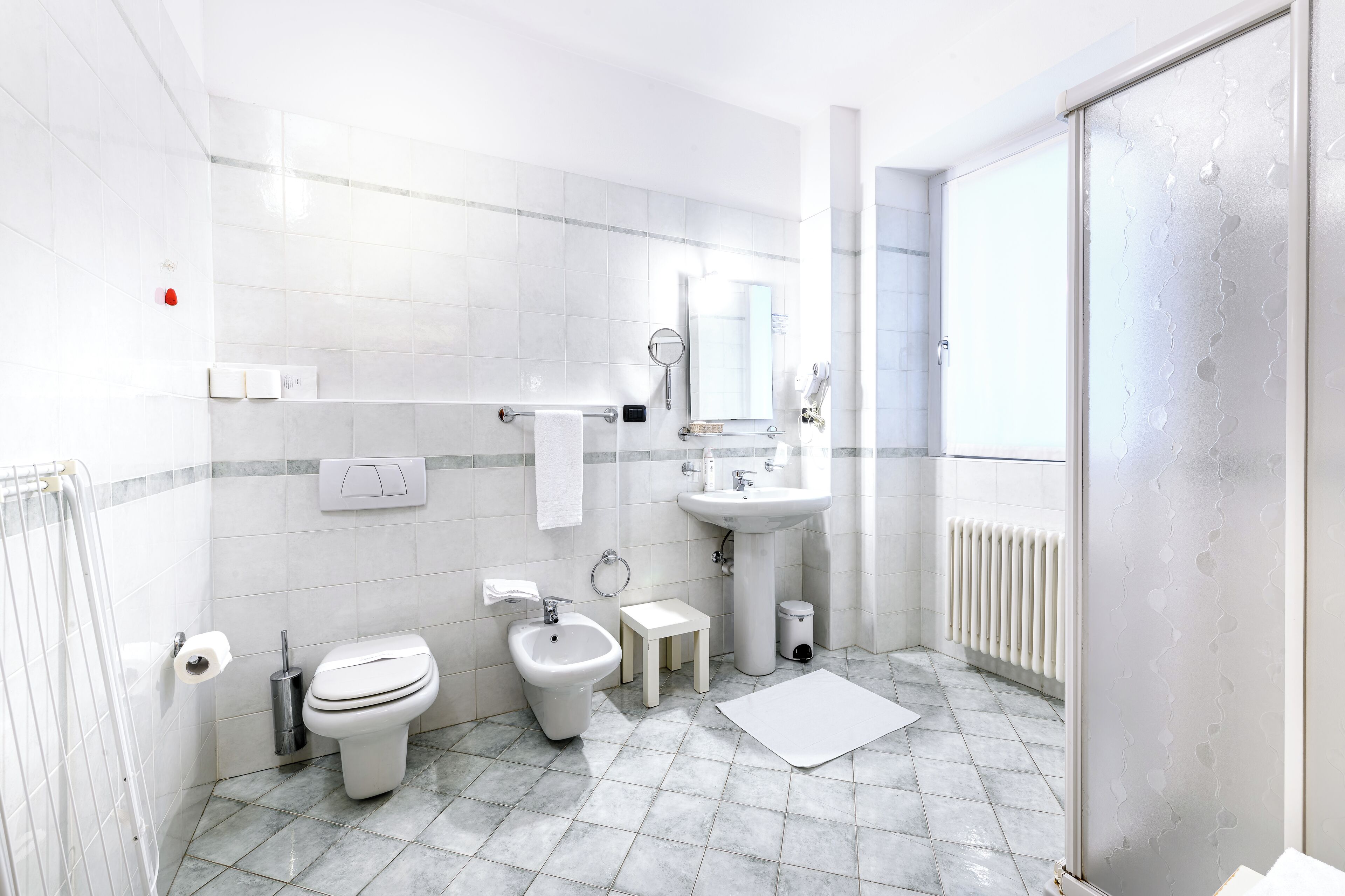 Une salle de bain moderne équipée de toilettes, d’un bidet, d’un lavabo et d’un petit tabouret.