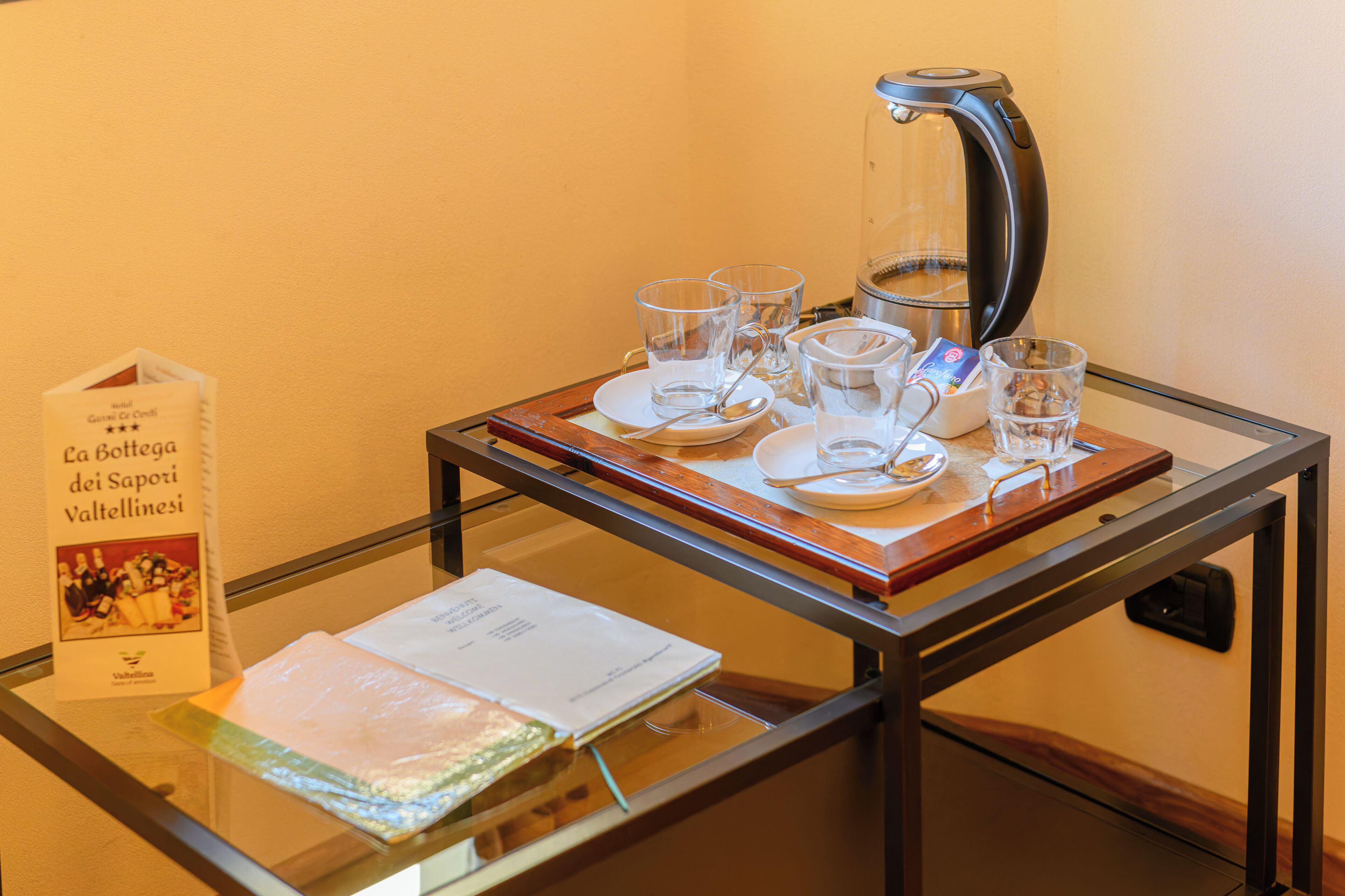 A glass table with a coffee maker, cups, and a menu.