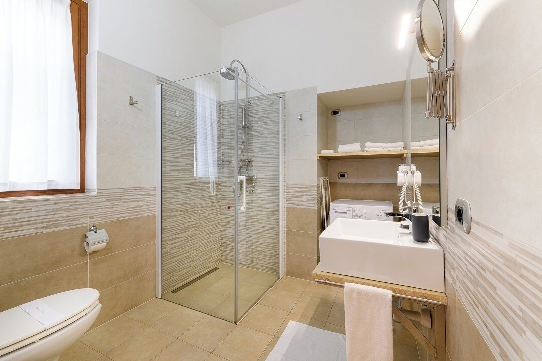 A modern bathroom with a glass-enclosed shower, a white sink, and a mirror.