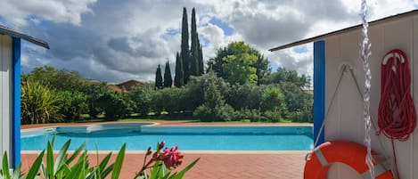 Una piscina al aire libre, sombrillas, sillones reclinables de piscina