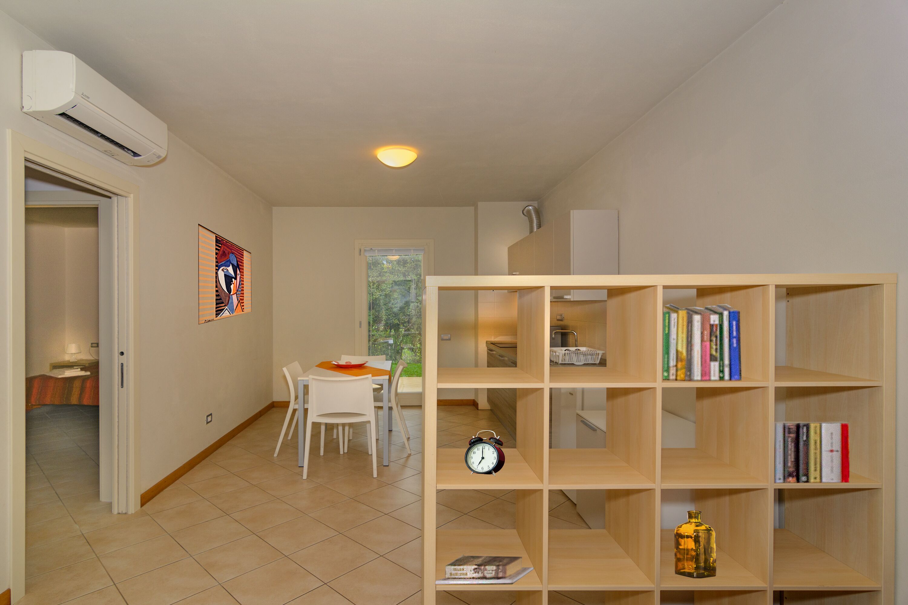 Una habitación con zona de comedor, una estantería y un aire acondicionado.