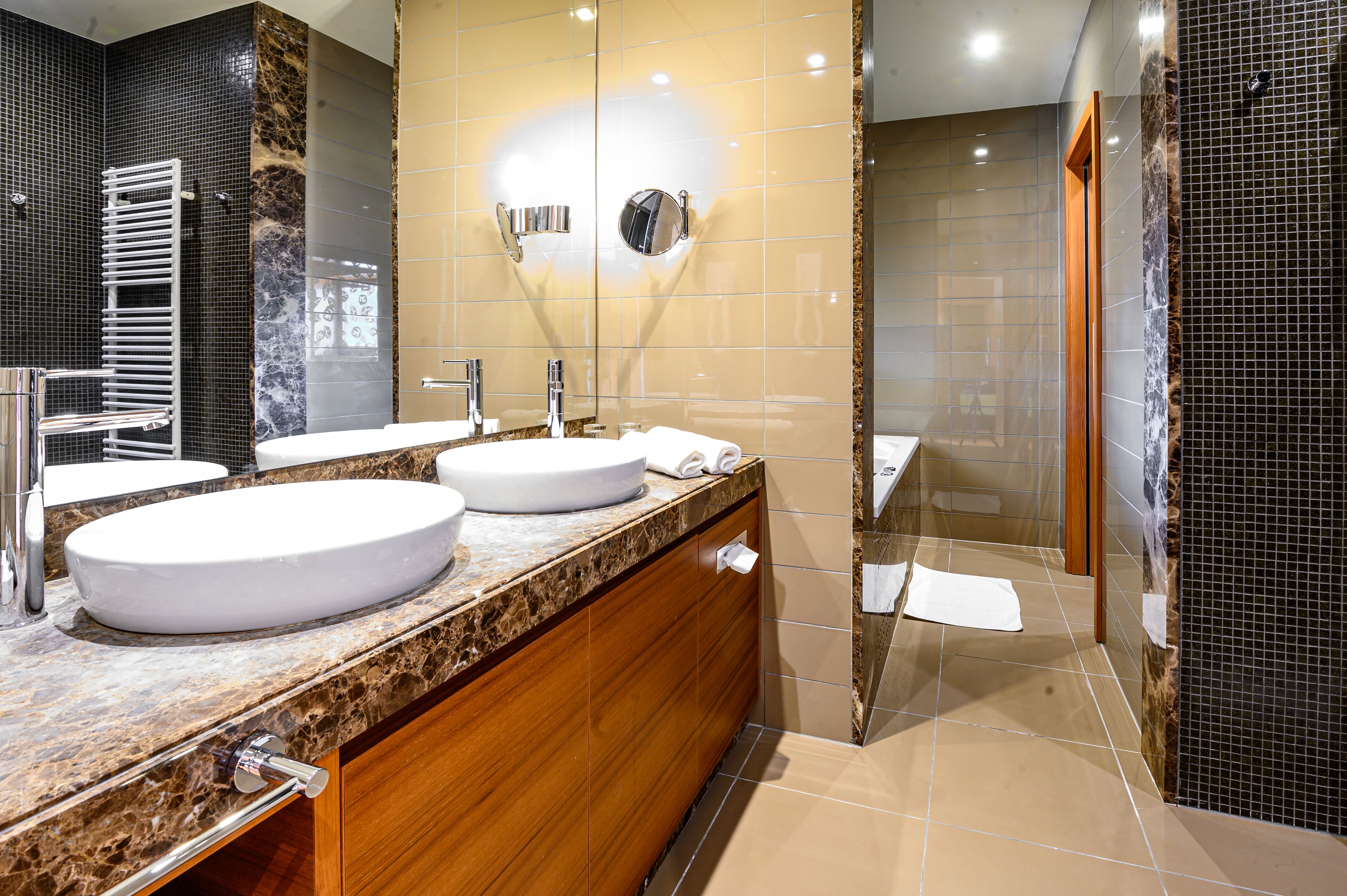 Un baño moderno con dos lavamanos, un espejo y cabina de ducha.