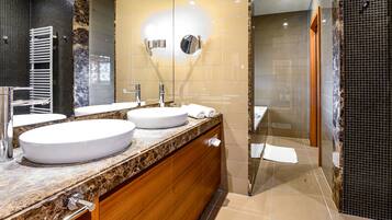 Un baño moderno con dos lavamanos, un espejo y cabina de ducha.