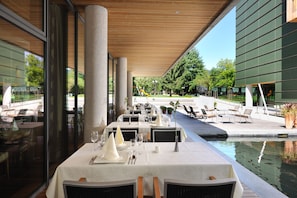 A dining area with tables set for a meal, a pool, and outdoor seating.