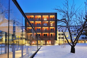 Un edificio moderno con varios balcones y ventanas amplias, rodeado de nieve.