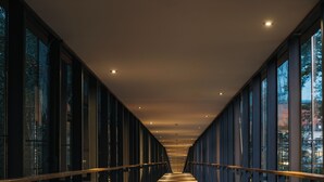 A corridor with a wooden floor and glass railings, leading to a bright interior space. - Hotel Balnea Superior – Terme Krka (Dolenjske Toplice)