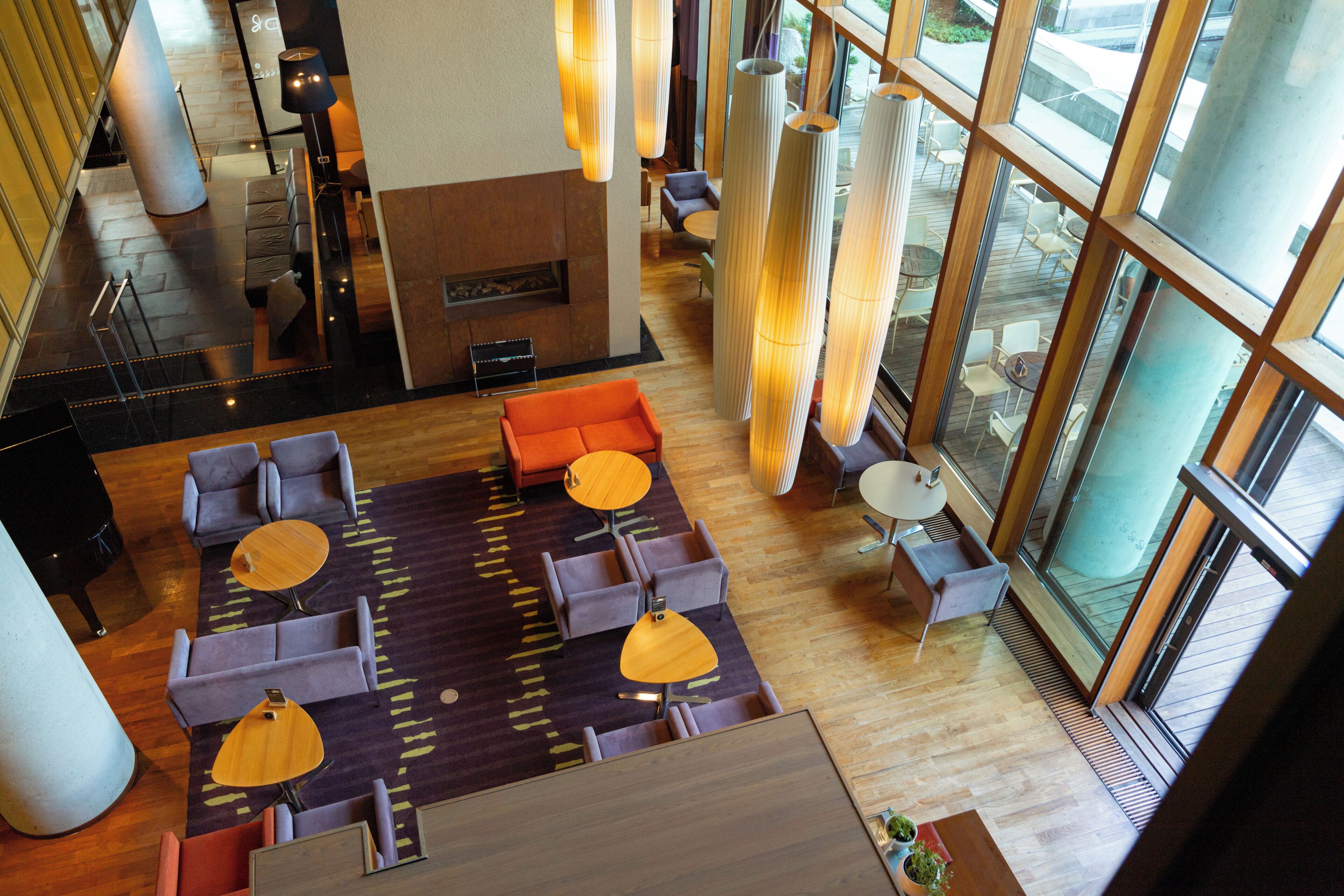 A spacious lobby with a central seating area, a piano, and large windows providing natural light.